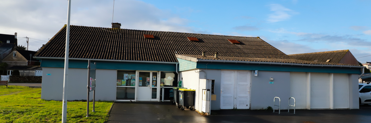 Bâtiment avec toit en pente, entrées et parking, marque au sol.