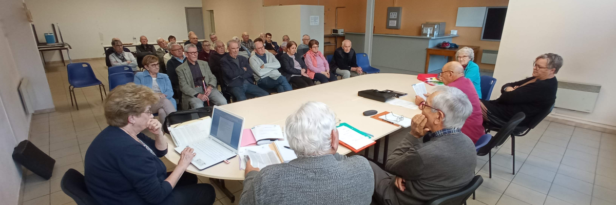 Réunion autour d'une table avec ordinateur portable, documents et chaises.