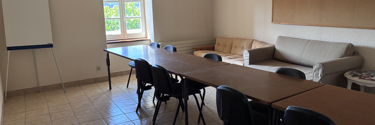 Salle avec table, chaises, canapé, tableau blanc et fenêtre.