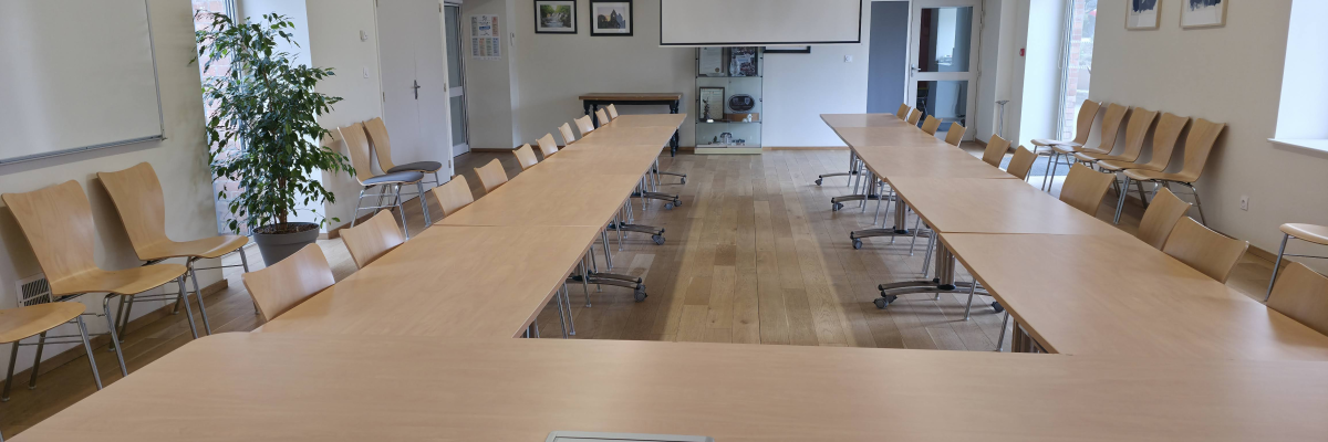 Salle de réunion avec table, chaises, vidéoprojecteur et tableau blanc.