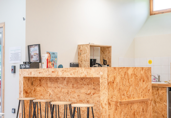 Comptoir en bois avec tabourets, téléphone, imprimante et étagères.