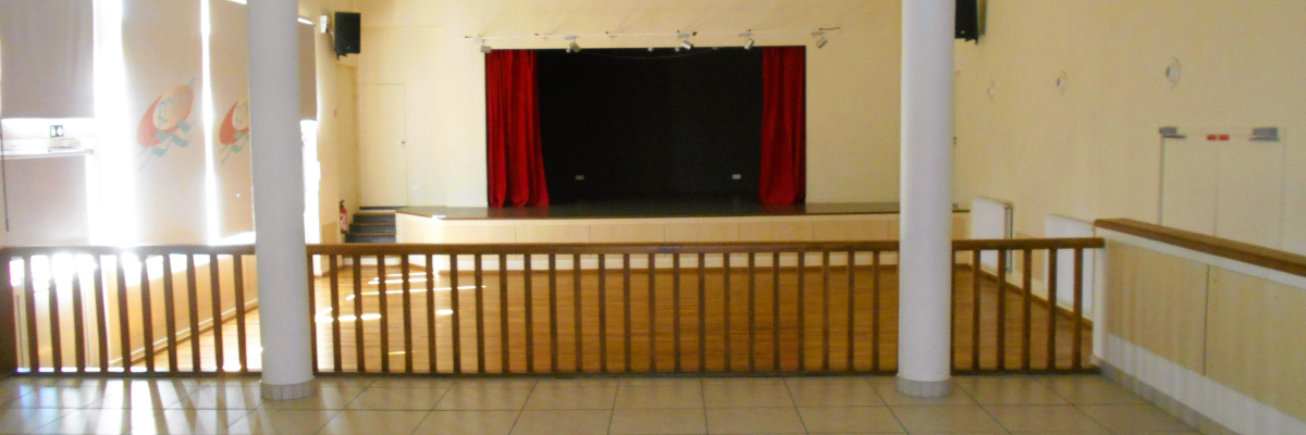 Salle avec scène, rideaux, rampes, et haut-parleurs.