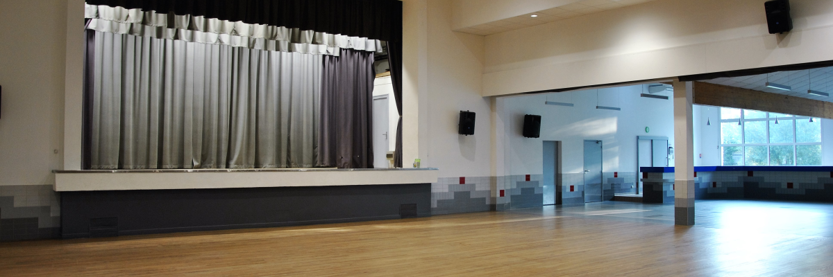 Salle avec scène, rideaux, parquet, éclairages et haut-parleurs.