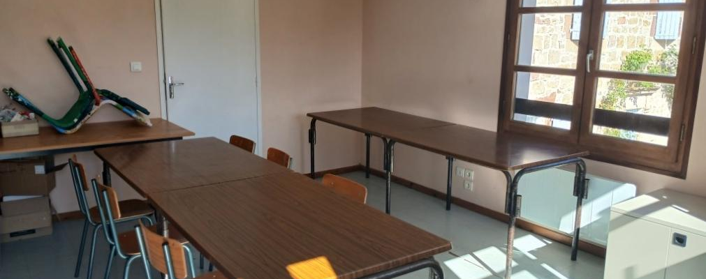 Salle avec tables, chaises, porte et fenêtres.
