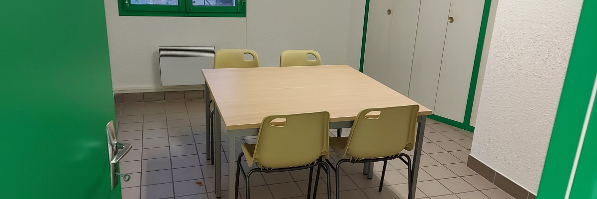 Salle avec table, chaises, radiateur et armoires.