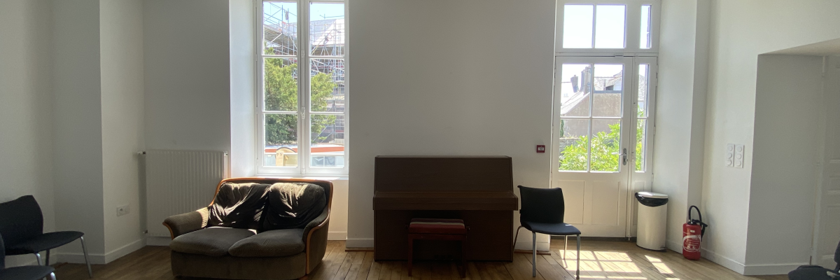 Salle avec canapés, chaises, radiateur, poubelle, et fenêtre.