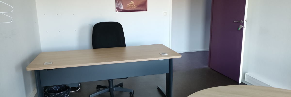 Bureau avec table, chaise, corbeille à papier et affiche.