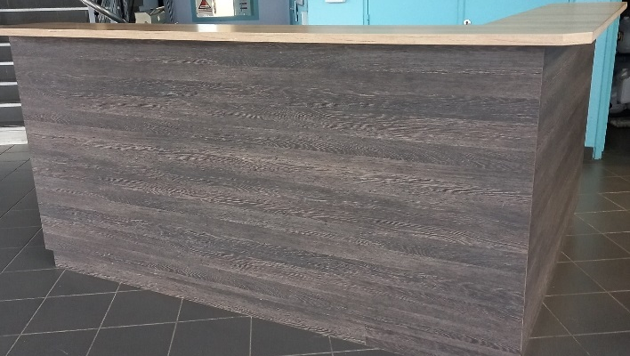 Comptoir en bois avec plan de travail, sols carrelés, escaliers et murs peints.