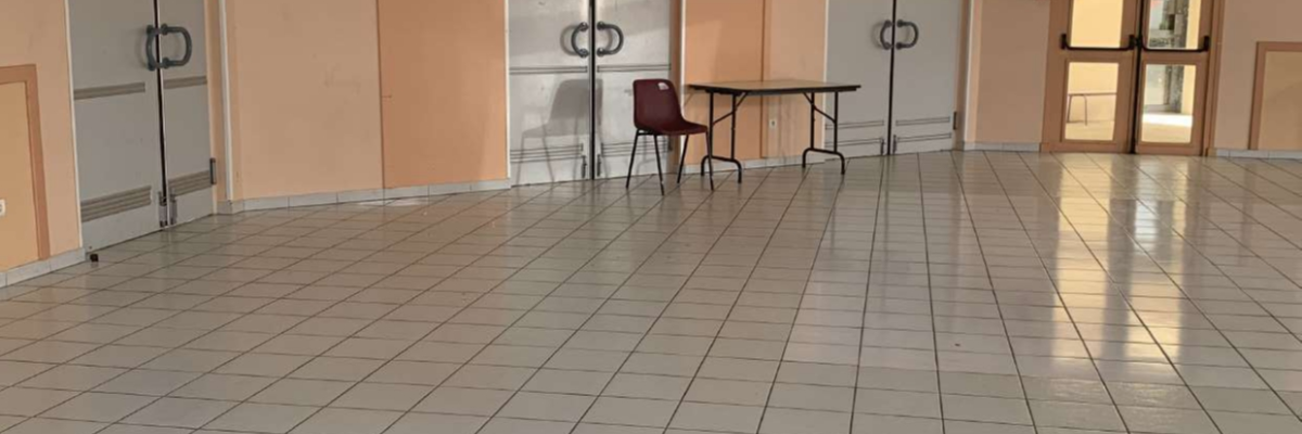 Salle avec tables, chaises, portes et détecteurs de fumée.