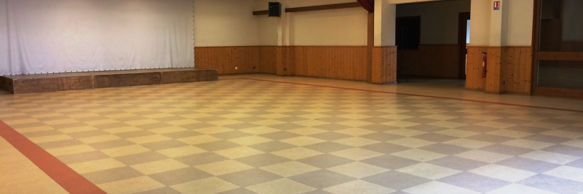 Salle spacieuse avec sol carié, murs en bois, éclairage au plafond et rideaux blancs.