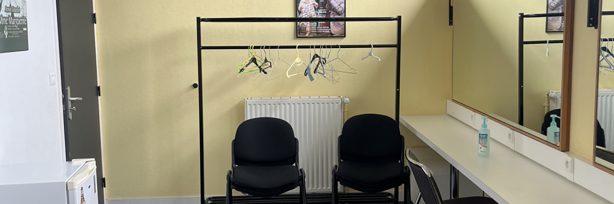 Salle d'attente avec chaises, radiateur, comptoir et miroir.