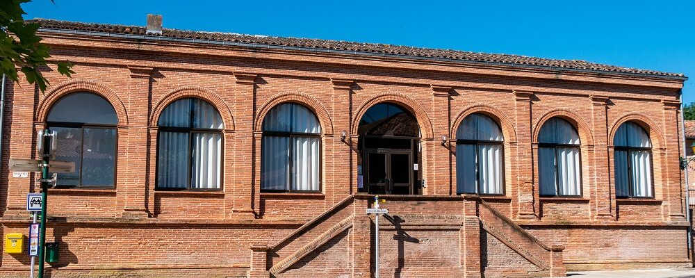 Bâtiment en brique avec fenêtres, porte d'entrée et escaliers.