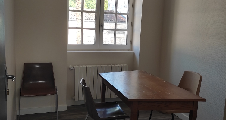 Pièce avec table, quatre chaises, radiateur et fenêtre.