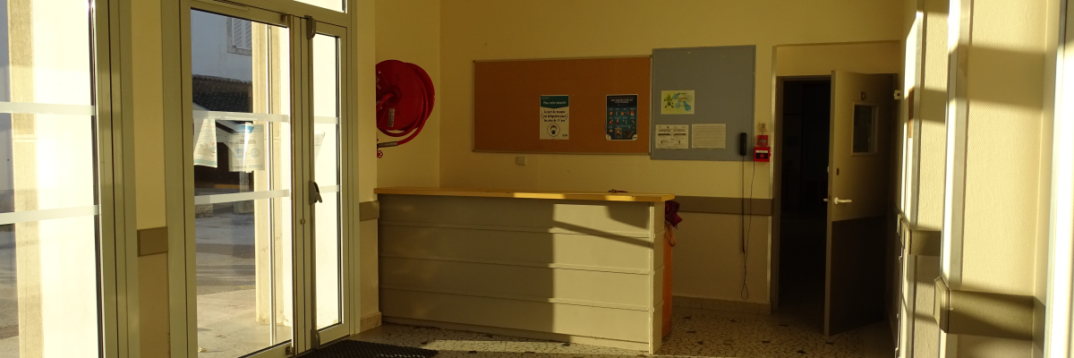 Pièce avec porte vitrée, comptoir, distributeurs et deux paillassons.