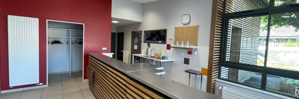 Cuisine avec comptoir, tabourets, étagères, horloge, radiateur, porte et fenêtre.