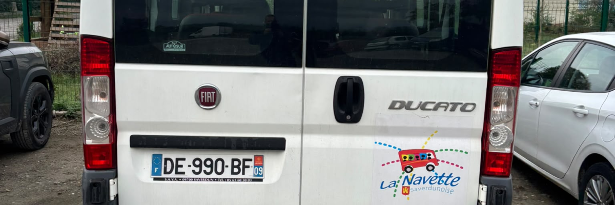 Fourgon blanc avec portes arrière ouvertes, plaque d'immatriculation visible.