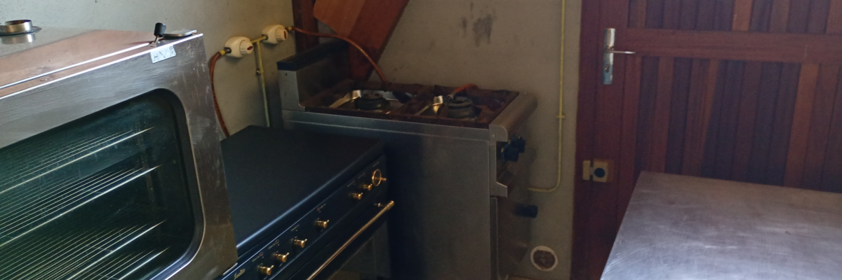 Cuisine avec four, plaque de cuisson, porte et tuyaux.