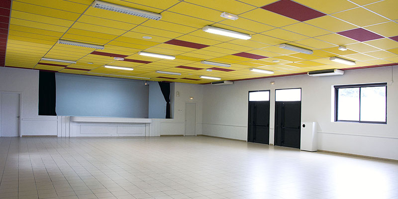 Salle vide avec plafond jaune, murs blancs, portes noires, fenêtres et comptoir.