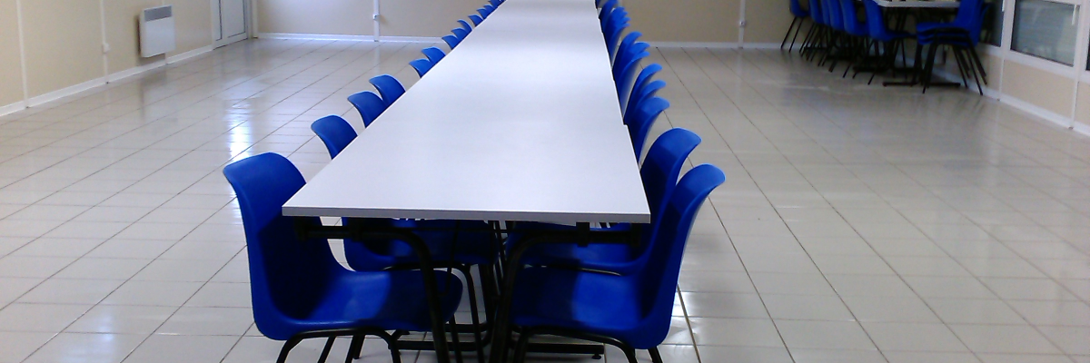 Salle avec tables, chaises et placard.