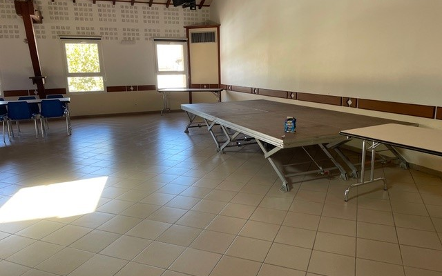 Salle de réunion avec tables, tables pliantes, chaises, et bouteilles d'eau.