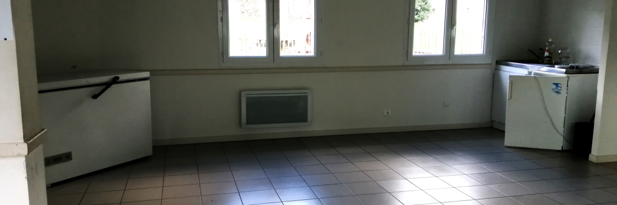 Pièce avec carrelage, fenêtres, radiateur, évier, plinthe et prises électriques.