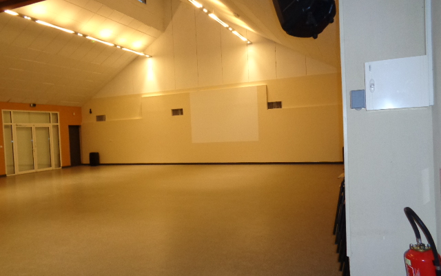 Salle vide avec éclairage, pupitre, extincteur et prises électriques.