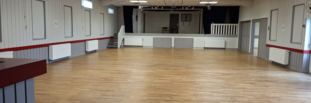 Salle vide avec parquet, murs blancs, portes, éclairage au plafond, escalier et bar.