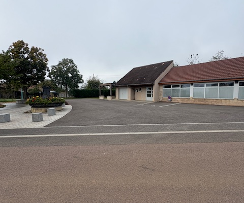 Parking avec bâtiment, arbre et rond-point.