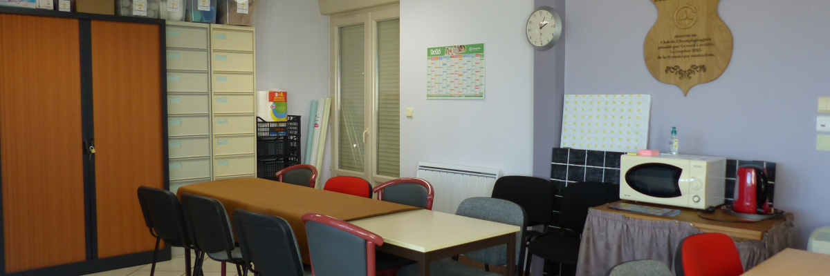 Salle avec tables, chaises, armoires, micro-ondes, calendrier, horloge et plaque murale.