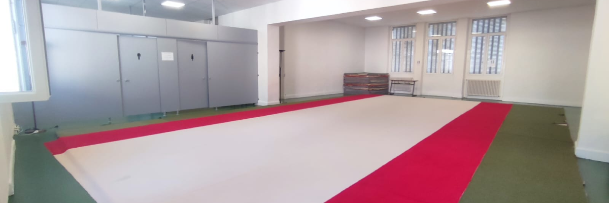 Salle avec tapis rouge, armoires grises, radiateur et fenêtre.