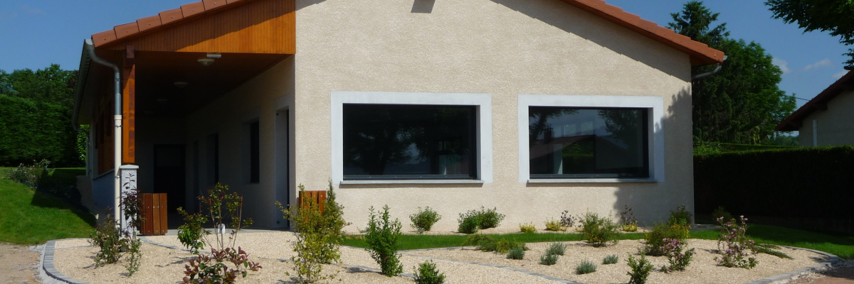 Maison beige avec toit rouge, fenêtres, porte vitrée, allée et plantes.