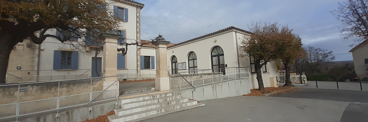 Bâtiment avec escaliers, rampes et portails, entouré d'arbres.