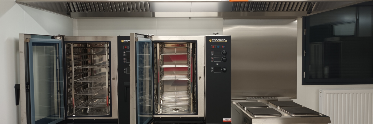 Cuisine avec fours, plan de travail, radiateur et hotte.