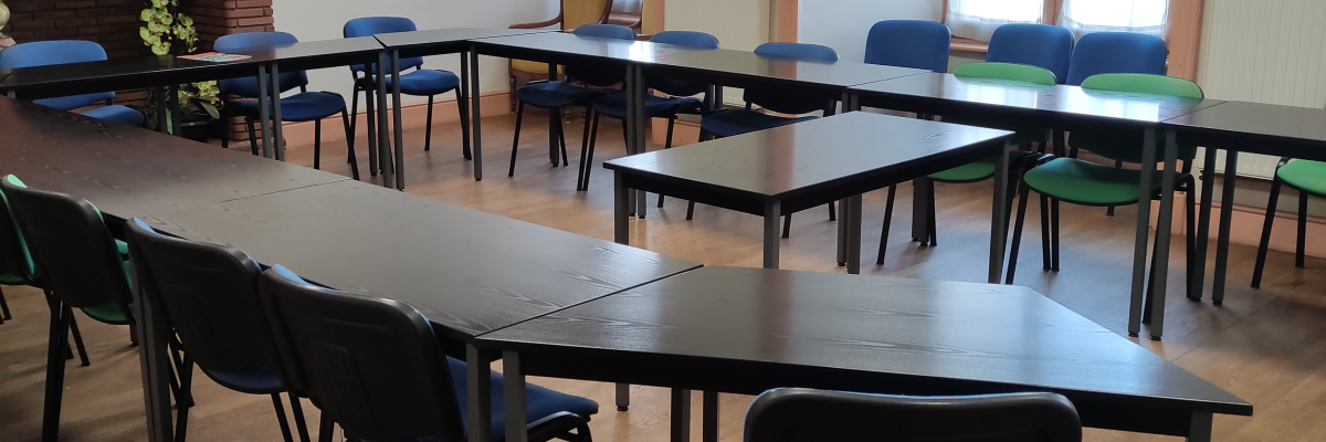 Salle de classe avec tables, chaises, tableau blanc et armoire.