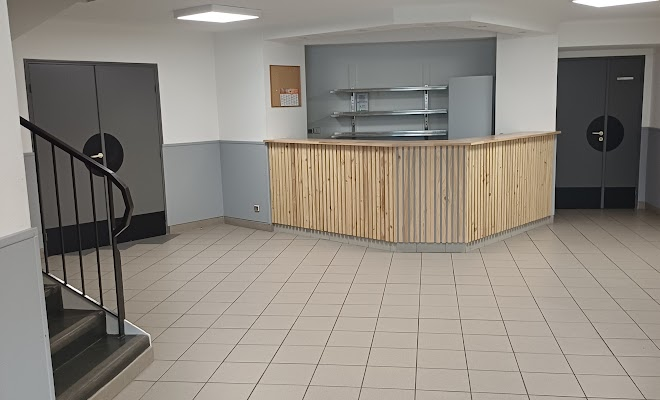 Pièce avec comptoir en bois, plan de travail, placards, escaliers métalliques et sol carrelé.