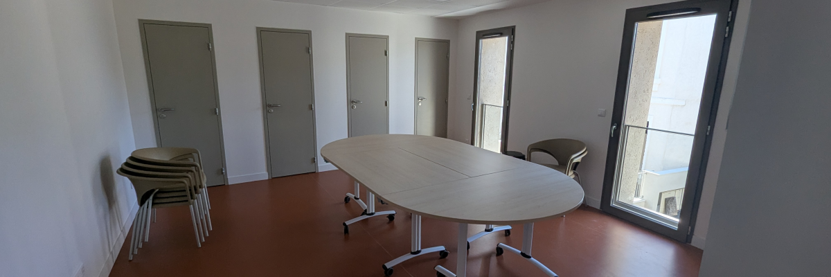 Salle avec table ovale, chaises, portes et fenêtre.