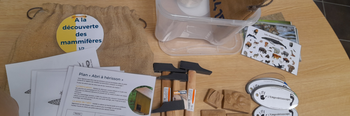 Table avec outils, cartes, documents, sac en toile et boîte en plastique.