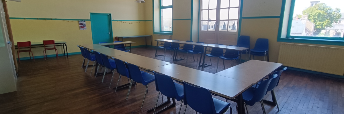 Salle avec tables, chaises, fenêtres et portes.