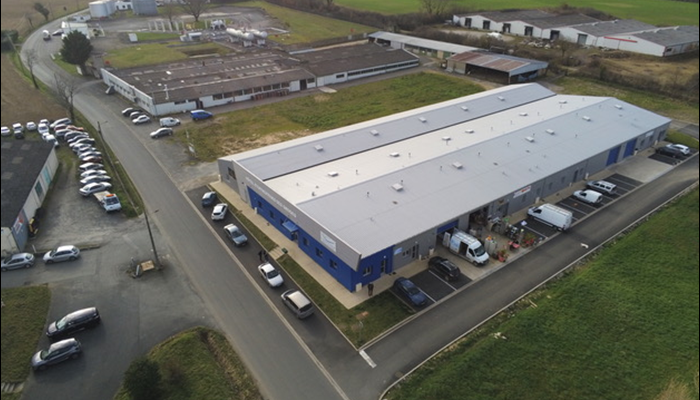 Vues aériennes d'un ensemble de bâtiments commerciaux et industriels, avec des véhicules garés et des terrains environnants.