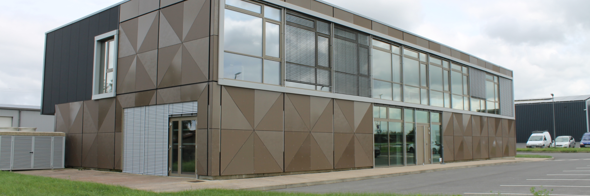 Bâtiment avec panneaux géométriques, grandes fenêtres et porte d'entrée.