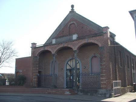 Bâtiment en brique avec trois arches et une porte centrale.
