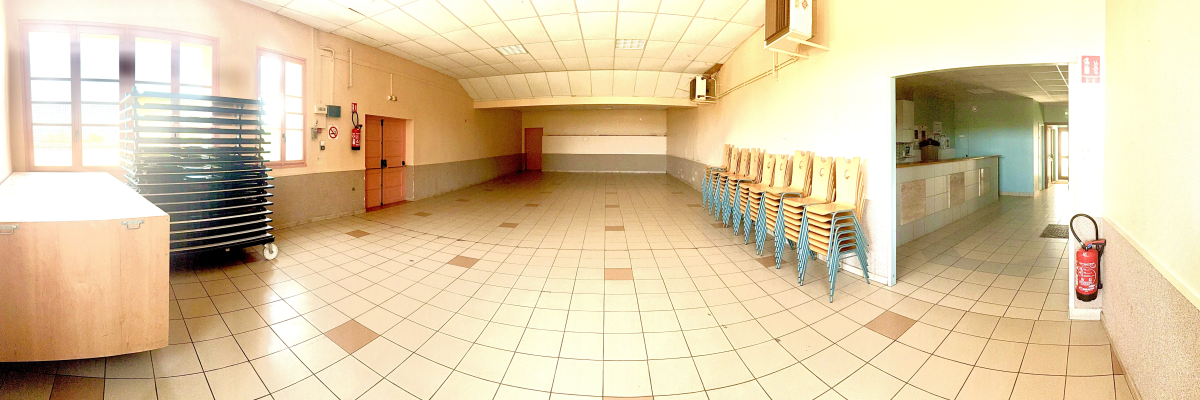 Salle vide avec chaises, table, extincteur, et fenetres avec store.