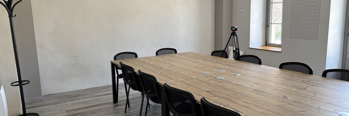 Salle avec table, chaises, trépied et porte-manteau.