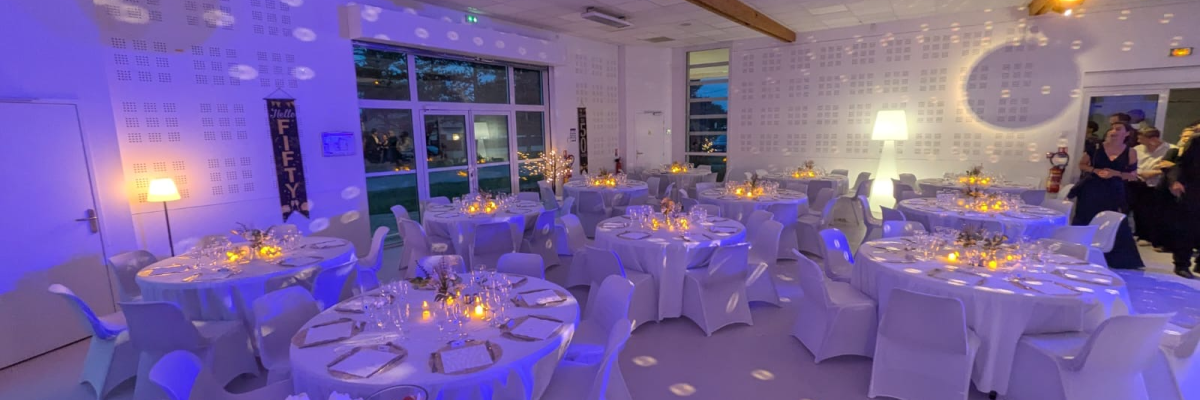 Salle de réception avec tables, chaises, luminaires et déco lumineuse.