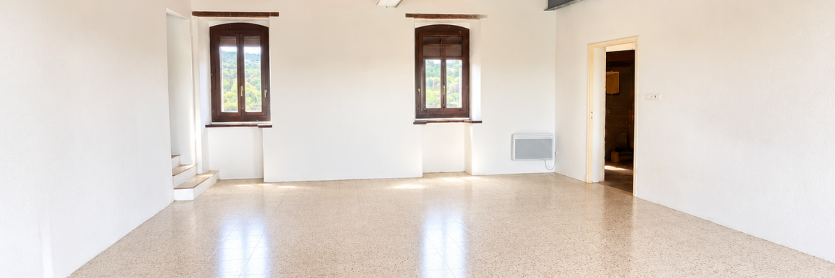Pièce vide avec sol lisse, plafond en bois, fenêtres et radiateur.