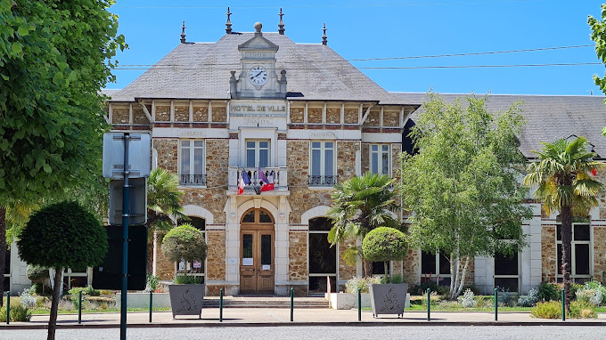 Façade d'un hôtel de ville avec horloge et drapeaux.