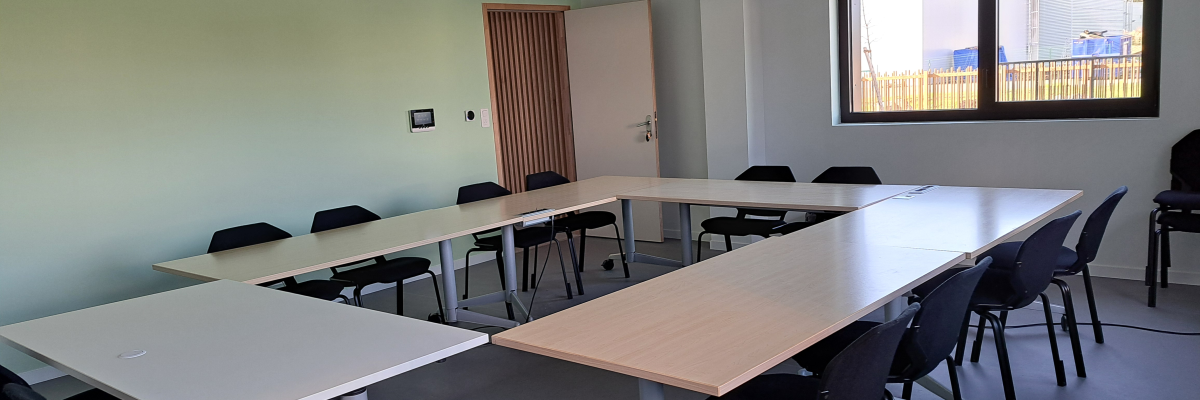 Salle avec tables, chaises, porte et fenêtres.