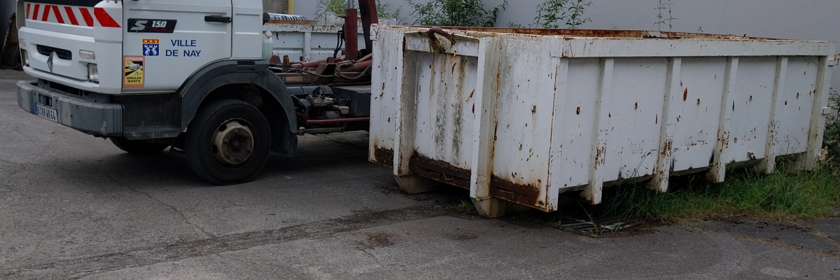 Camion avec grue et benne sur parking.