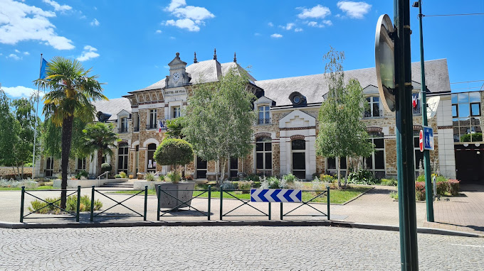 Bâtiment avec horloge, arbres, barrières, et panneaux de signalisation.