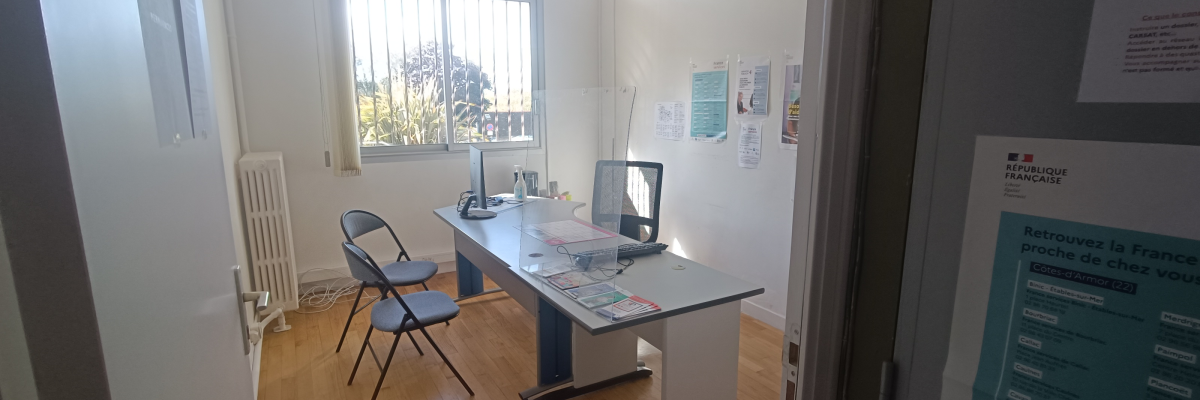 Bureau avec chaise, ordinateur, imprimante, radiateur et affiches murales.